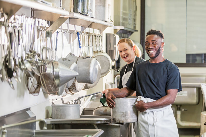 Deux jeunes gens souriants dans une cuisine d'apprentissage